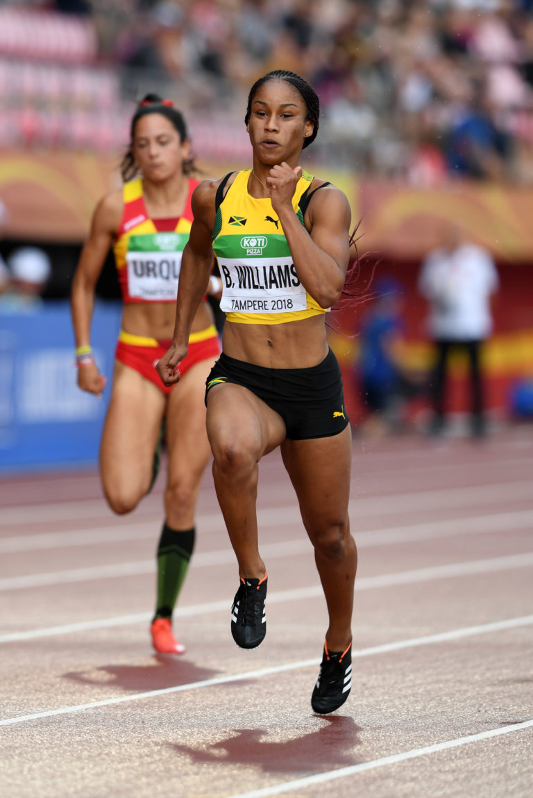 A female sprinter competing in a 100-meter race at the World U20 Championships in Tampere, Finland — representing excellence, determination, and athletic achievement featured by HSI.net.
