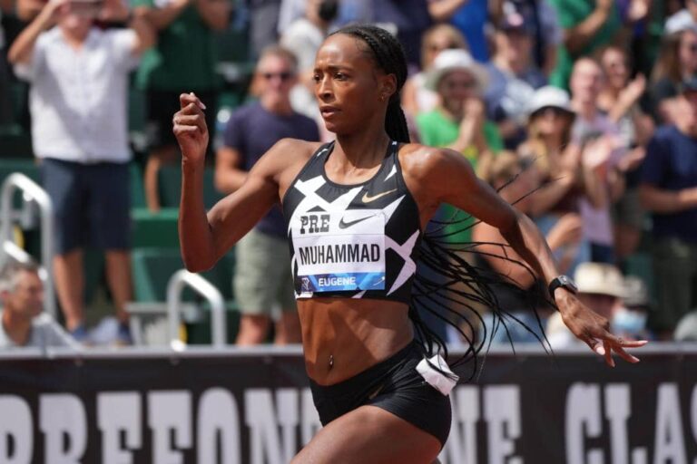 Professional track and field athlete sprinting with power and determination during a major competition, showcasing elite athletic performance and focus.