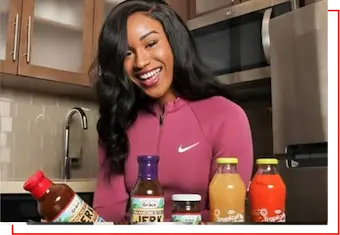 Smiling woman in a modern kitchen surrounded by branded products, showcasing successful partnerships — representing Brand Management, Marketing, and Endorsements by HSI.net.